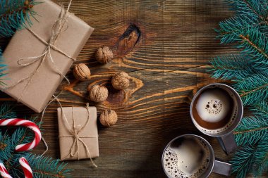 İki fincan kapuçino Noel hediyeleri, fındık, koni ve köknar dalı ahşap arka plan üzerinde kapat