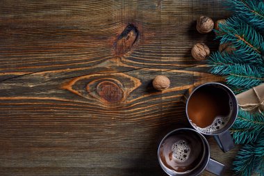 İki fincan kapuçino Noel hediyeleri, fındık, koni ve köknar dalı ahşap arka plan üzerinde kapat