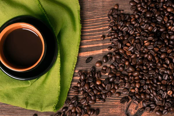 Ahşap arka planda kahve fincanı ve kahve çekirdeği. Üst görünüm.