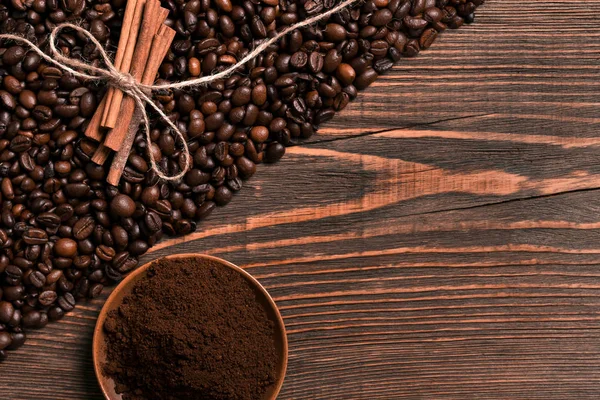 Kahve çekirdekleri, tarçın ve rustik ahşap üzerinde çekilmiş kahve
