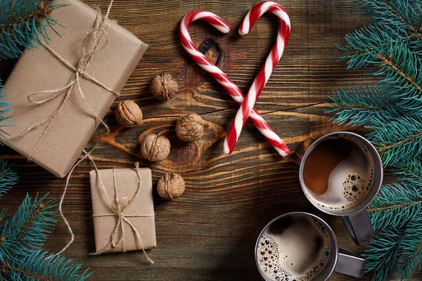İki fincan kapuçino Noel hediyeleri, fındık, koni ve köknar dalı ahşap arka plan üzerinde kapat