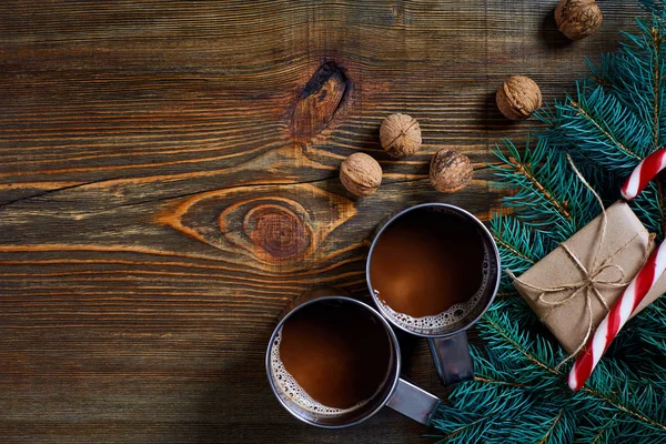 İki fincan kapuçino Noel hediyeleri, fındık, koni ve köknar dalı ahşap arka plan üzerinde kapat
