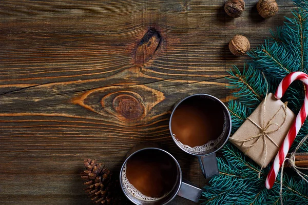 İki fincan kapuçino Noel hediyeleri, fındık, koni ve köknar dalı ahşap arka plan üzerinde kapat