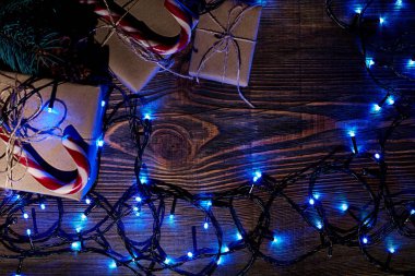 Köknar ağacı dalı Noel ışıkları, hediye kutusu ve şeker ile kopya alanı ile ahşap arka plan üzerinde köpekler.