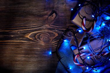 Köknar ağacı dalı Noel ışıkları, hediye kutusu ve şeker ile kopya alanı ile ahşap arka plan üzerinde köpekler.