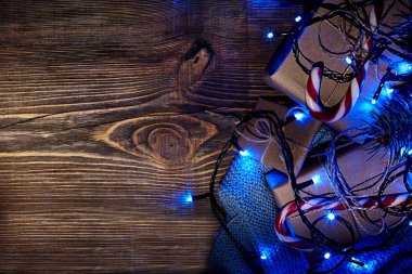 Köknar ağacı dalı Noel ışıkları, hediye kutusu ve şeker ile kopya alanı ile ahşap arka plan üzerinde köpekler.