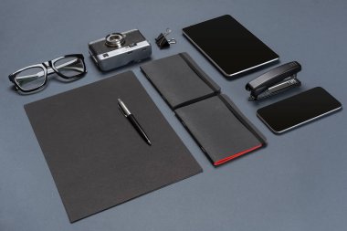 Siyah ofis aksesuarları, gözlük, eski fotoğraf makinesi ve tablet gri arka plan üzerinde bir dizi