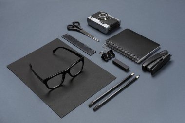 Birtakım siyah ofis aksesuarları, gözlük ve gri arka plan üzerinde eski fotoğraf makinesi