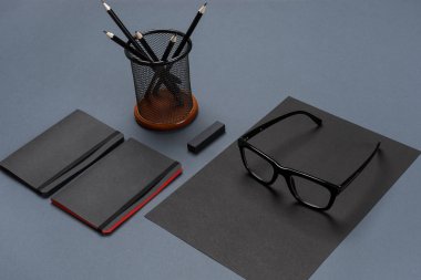 Gri bir arka planda, düz siyah ofis kırtasiye seti yatıyordu