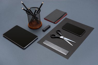 Gri bir arka planda, düz siyah ofis kırtasiye seti yatıyordu