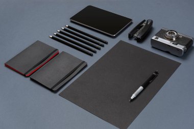 Gri bir arka planda, düz siyah ofis kırtasiye seti yatıyordu