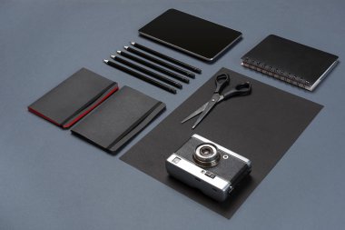 Gri bir arka planda, düz siyah ofis kırtasiye seti yatıyordu