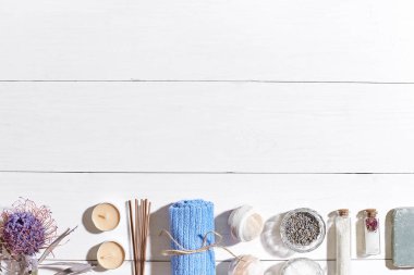 Spa Ürünleri. Banyo tuzları, kuru çiçekler lavanta, sabun, mumlar ve havlu. Düz beyaz ahşap zemin, üstten görünüm üzerinde yatıyordu.