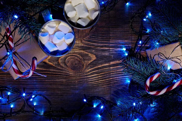 Bebida caliente de Navidad. Cacao con malvavisco, guirnalda y ramas de abeto sobre un fondo de madera. Vista superior — Foto de Stock