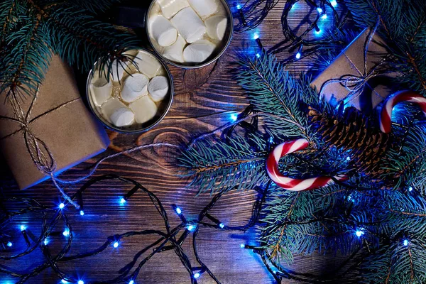 Christmas hot drink. Cocoa with marshmallow, garland and spruce branches on a wooden background. Top view — Stock Photo, Image