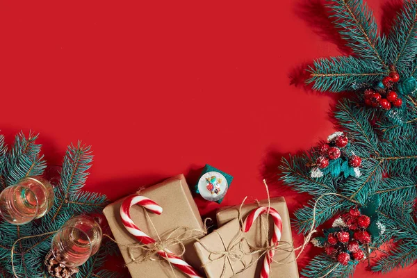 Çam kozalakları, çam dalları ve hediye kutuları kırmızı zemin üzerine yığını Noel bileşimi