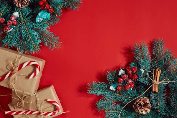 Çam kozalakları, çam dalları ve hediye kutuları kırmızı zemin üzerine yığını Noel bileşimi