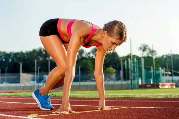 Joven atleta en posición de salida lista para comenzar una carrera en pista de carreras . — Foto de Stock