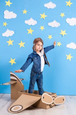 Küçük çocuk kız pilotlar kostümlü oynayan ve bulutların üzerinde uçan bir rüya.