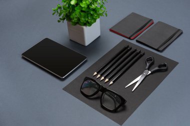 Gri bir arka planda, düz siyah ofis kırtasiye seti yatıyordu