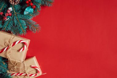 Çam kozalakları, çam dalları ve hediye kutuları kırmızı zemin üzerine yığını Noel bileşimi