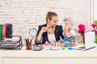 Anne ve bebek kızı ile oynamaya ve dizüstü bilgisayarınızla evde çalışma iş kadını.