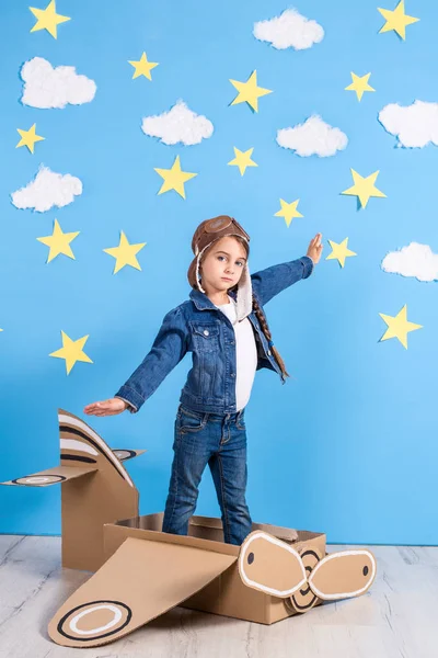 Little child girl in a pilots costume is playing and dreaming of flying over the clouds.