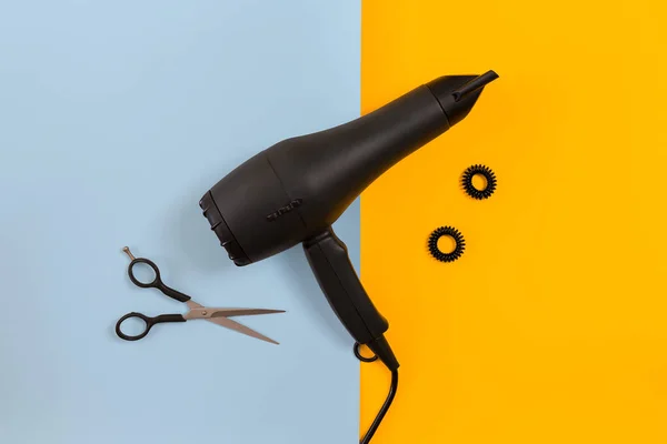 Cabello estilizado con tijeras, secadora y herramientas en barbería sobre papel azul y amarillo vista superior maqueta — Foto de Stock