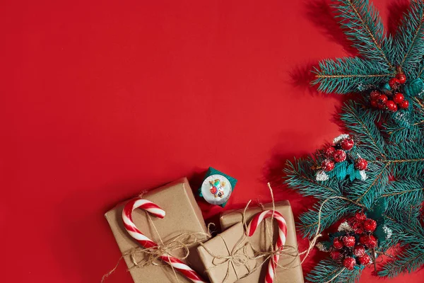 Çam kozalakları, çam dalları ve hediye kutuları kırmızı zemin üzerine yığını Noel bileşimi