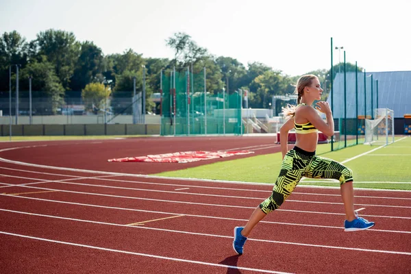 Koşu ve atletik yolda stadyum üzerinde çalışan güzel bir genç kadın egzersiz.