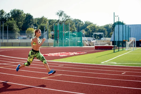 Koşu ve atletik yolda stadyum üzerinde çalışan güzel bir genç kadın egzersiz.