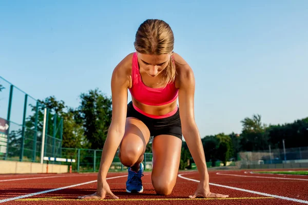 Joven atleta en posición de salida lista para comenzar una carrera en pista de carreras . — Foto de Stock