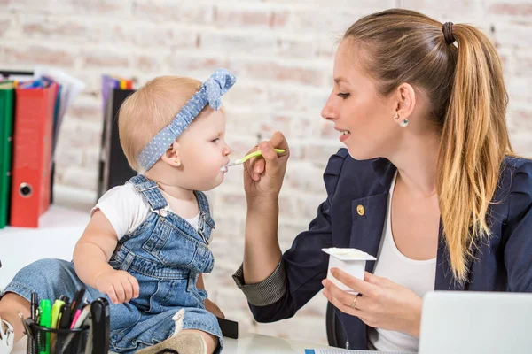 Anne ve bebek kızı ile oynamaya ve dizüstü bilgisayarınızla evde çalışma iş kadını.