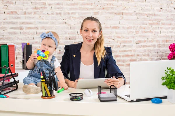 Mãe e mulher de negócios trabalhando com computador portátil em casa e brincando com sua menina . — Fotografia de Stock