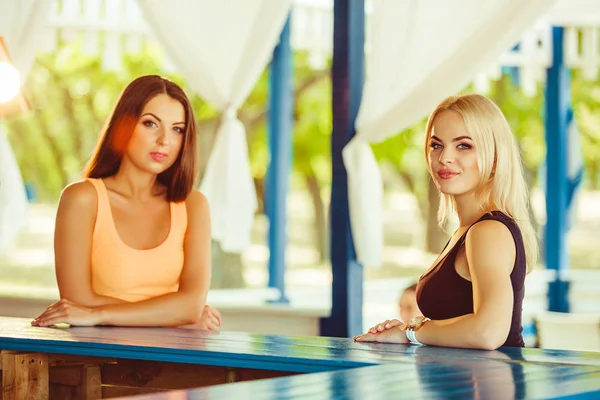 Duas meninas amigas se divertindo ao ar livre no verão. Mulher está esperando por seus coquetéis — Fotografia de Stock