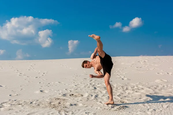 Porträt eines jungen Parkour-Mannes, der Flip oder Salto auf dem Sand macht. — Stockfoto