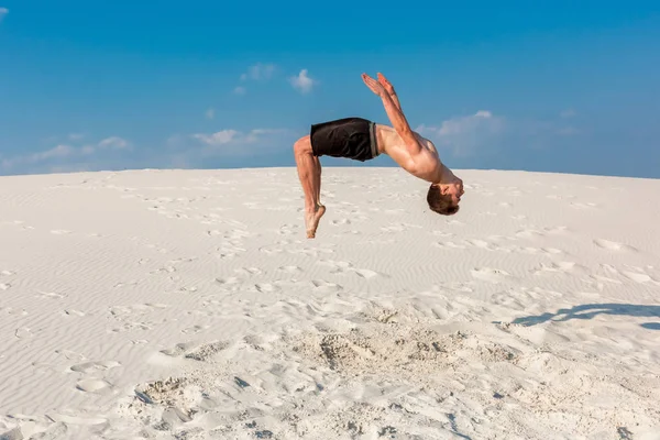 Giovane saltando sulla spiaggia con sabbia bianca e cielo blu brillante — Foto Stock