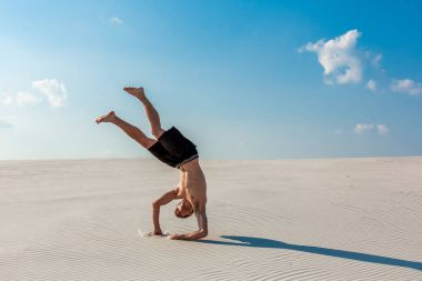 Genç adam plaj beyaz kum ve parlak mavi gökyüzü ile atlama