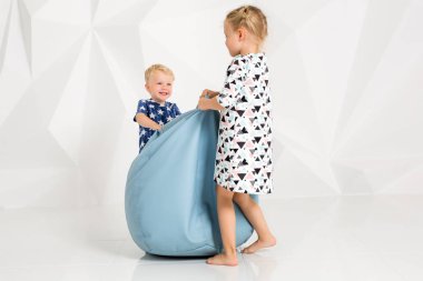 Oynama ve beyaz bir stüdyoda gülümseyen kardeş