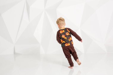 kahverengi bir süveter ve pantolon beyaz bir arka plan üzerinde küçük çocuk