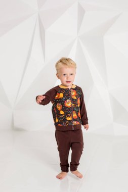kahverengi bir süveter ve pantolon beyaz bir arka plan üzerinde küçük çocuk