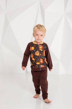 kahverengi bir süveter ve pantolon beyaz bir arka plan üzerinde küçük çocuk