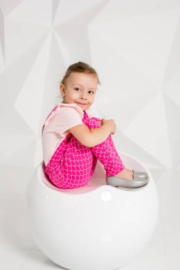 Sarı saçlı, beyaz arka plan üzerinde pembe tulum ile güzel küçük kız