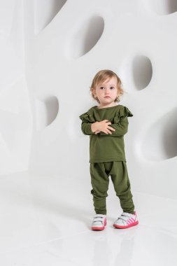 Studio beyaz duvarının yakınında duran yaş çocuk
