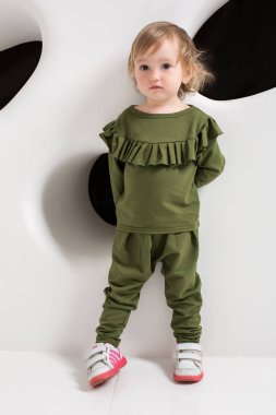 Studio beyaz duvarının yakınında duran yaş çocuk