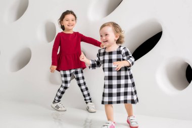 İki şık küçük kız birbirlerine beyaz duvar arka planda çalıştırın