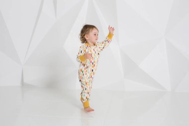 Studio beyaz duvarının yakınında duran yaş çocuk