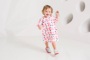 Yaş Çocuk Studio beyaz duvarının yakınında duran yaz elbise