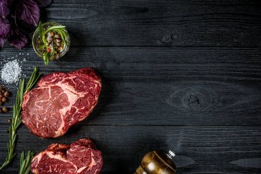 Taze çiğ et fesleğen ve biberiye siyah ahşap zemin üzerine bir delikanlı ile