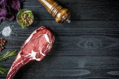 Taze çiğ et fesleğen ve biberiye siyah ahşap zemin üzerine bir delikanlı ile